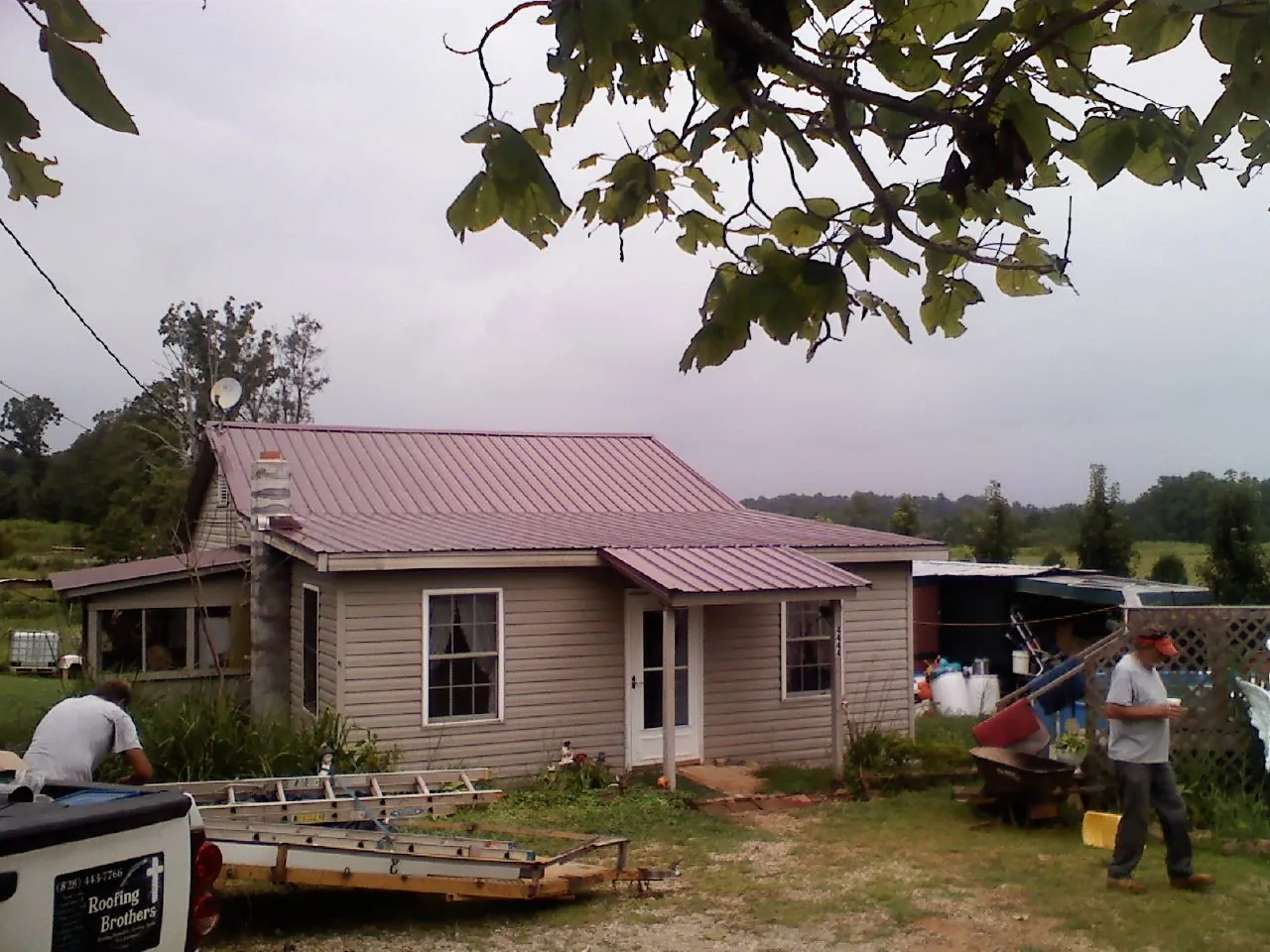 Crew finishing a mauve metal roof on a small farmhouse in Spencer